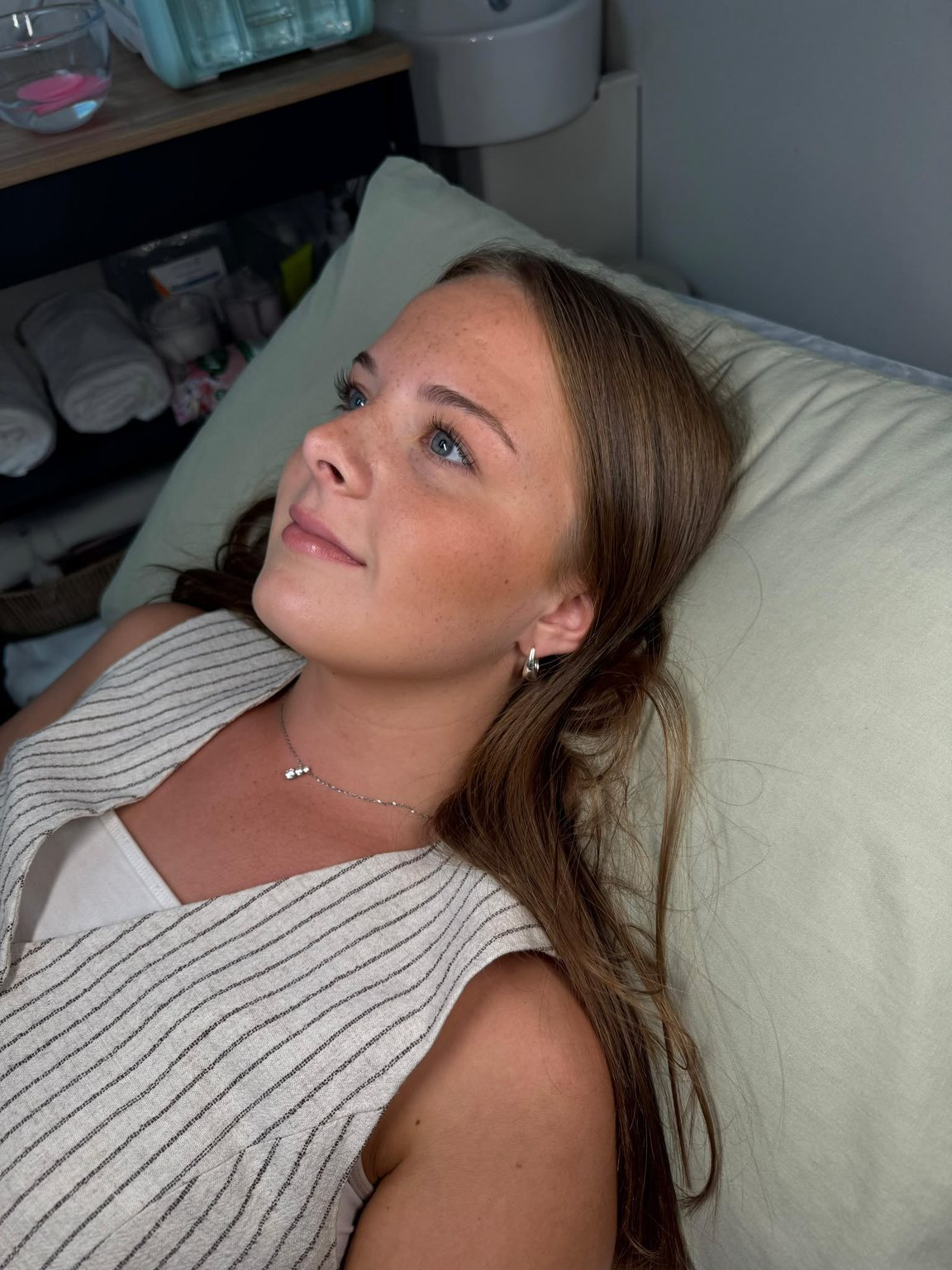 A client resting on the treatment couch after a skin treatment, showing an even, healthy complexion